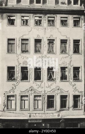 Vintage-Foto von Dresden. Altes Haus an der Moritzstraße Nr. 6. Deutschland. 1903 die fünfgeschossige, sechsfächerbreite Fassade zeigt eine schlichte Anordnung über dem komplett umgestalteten Erdgeschoss: Die Fenster umgeben unprofilierte Sandsteinwände. Die verputzten Flächen sind mit Rokoko-Ornamenten in appliziertem Stuck so verziert, dass durch die allgemeinen Pilaststreifen eine pyramidale Struktur erreicht wurde. Das Gebäude muss kurz nach der Belagerung von 1760 errichtet worden sein. Eine große Kanonenkugel ist in den Innenhof eingemauert. Stockfoto