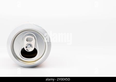 Ein horizontales Foto mit einer geneigten Bierdose mit einer detaillierten Ansicht der offenen Oberseite. Die Dose befindet sich auf der linken Seite gegen eine saubere weiße Rückseite Stockfoto