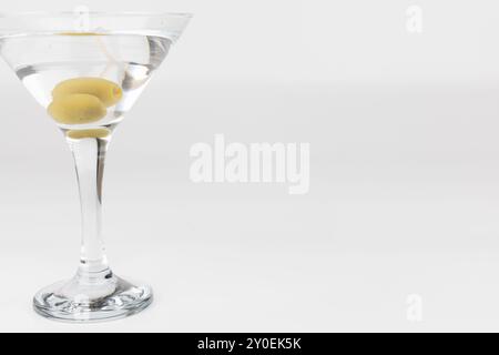 Eine horizontale Nahaufnahme eines Martini-Glases mit zwei Oliven, links vom Rahmen platziert. Der weiße Hintergrund sorgt dafür, dass der Fokus auf t bleibt Stockfoto