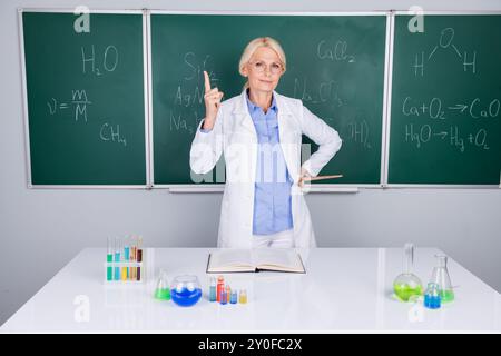 Foto einer charmanten, intelligenten Professorin, Senior Frau, die Chemie lehrt, isoliert auf grünem Bretthintergrund Stockfoto