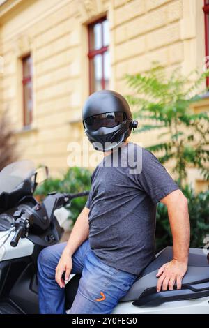 Biker in einem Helm und Leder Schutzausrüstung sitzt auf einem Motorrad, ein sportliches schnelles Motorrad Stockfoto
