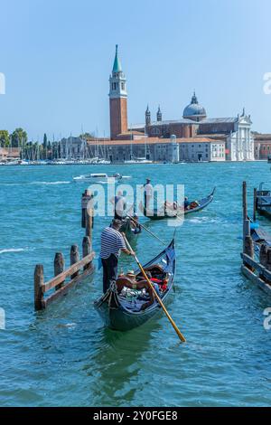 Venedig, Italien - 26. Juli 2024: Gondeln gegen die Insel San Giorgio in Venedig, Italien. Die Gondel ist der attraktivste Touristenverkehr in Venedig. T Stockfoto