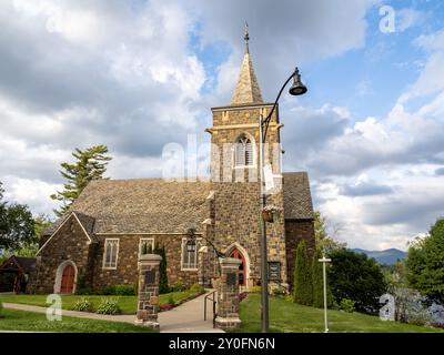 Entdecken Sie die ruhige Schönheit der Adirondack Community Church in Lake Placid, New York, mit atemberaubendem Blick auf Mirror Lake und das majestätische Adiron Stockfoto