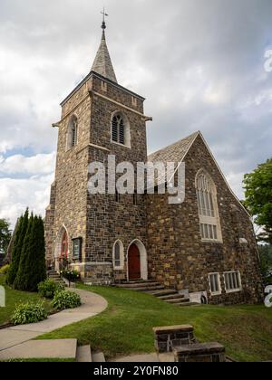 Entdecken Sie die ruhige Schönheit der Adirondack Community Church in Lake Placid, New York, mit atemberaubendem Blick auf Mirror Lake und das majestätische Adiron Stockfoto