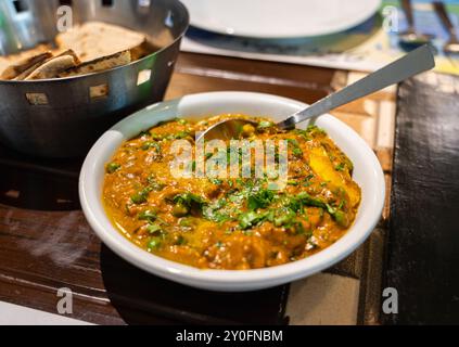 Selektiver Fokus auf Blumenkohlerbsen Masala Soße oder Gobi Matar Masala, serviert in einer weißen Keramikschale auf einem Esstisch im Restaurant. Stockfoto