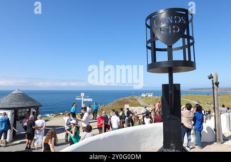 Lands End, Cornwall. Besucher stehen an einem geschäftigen Sommertag neben dem Lands End Schild für ein Foto an. Stockfoto