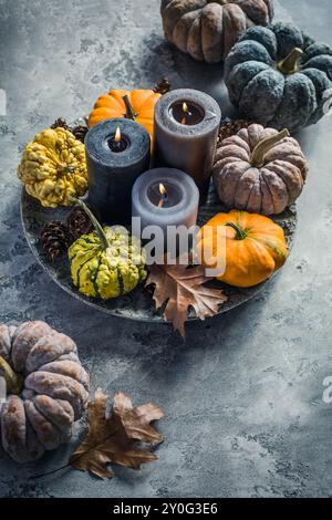 Stillleben im Herbst mit Kürbissen und Kerzen auf hölzernem Hintergrund. Thanksgiving Wohndekoration. Stockfoto