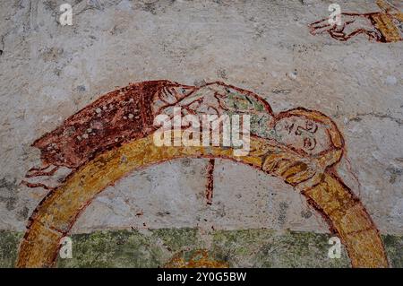 Die Heilige Katharina von Alexandria blickt auf die Hand Gottes, während sie mit überkreuzten Unterarmen auf einem brechenden Rad liegt. Detail des mittelalterlichen Freskos, Abbazia di Piona (Abtei Piona), Colico, Lombardei, Italien. Das Fresko ist insofern ungewöhnlich, als die Heilige Katharina häufiger als triumphierend mit dem zerstörten Rad dargestellt wird. Stockfoto