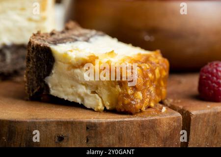 Käsekuchen mit Schokoladenschwammkuchen und Erdnüssen in Karamell, köstliches Dessert mit Erdnüssen und Käsesahne Stockfoto