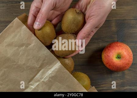 Weibliche Hände legen Früchte in einen Papierbeutel, um die Verwendung umweltgefährdender Plastikbeutel zu begrenzen Stockfoto