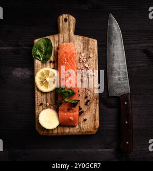 Roher roter Fisch Lachsfilet mit Kräutern und Zitrone auf einem Schneidebrett bereit für das Kochen gesundes Abendessen, Blick von oben Stockfoto