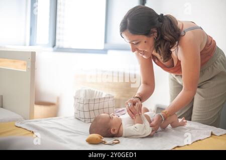 Eine Frau wechselt die Windel eines Babys auf einem Bett im Schlafsaal. Mutterschaft und Familie. Stockfoto