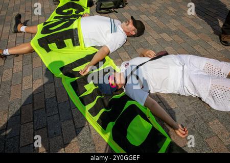 Windsor, Großbritannien, 1. September 2024. Demonstranten nehmen an einem Sterben Teil, indem sie sich auf den Boden legen, der mit einem Protestbanner bedeckt ist. Mitglieder der Extinction Rebellion halten eine dreitägige Demonstration vor dem Gelände von Windsor Castle ab. Die Fraktion fordert die neue Labour-Regierung auf, eine Bürgerversammlung zur Bekämpfung des Klimawandels einzurichten. Quelle: James Willoughby/Alamy Live News Stockfoto