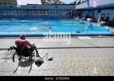 Kiew, Oblast Kiew, Ukraine. August 2024. Mann im Rollstuhl, der auf 1000 Metern schwimmende Wettkämpfe von einem Team mit ukrainischen Soldaten sieht, die an der Front verletzt wurden. Viele der Soldaten verloren im Kampf Gliedmaßen, während andere einen Teil ihres Körpers gelähmt hatten. Schwimmen hilft ihnen bei den Erholungsprozessen. (Kreditbild: © Andreas Stroh/ZUMA Press Wire) NUR REDAKTIONELLE VERWENDUNG! Nicht für kommerzielle ZWECKE! Stockfoto