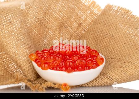 Roter Kaviar auf einer Keramikplatte auf einer Jute-Serviette, Makro. Stockfoto