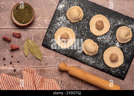 Lebensmittelfotografie von Zutaten von hausgemachten Teig, rohem und gehacktem Huhn, Zwiebeln, Knoblauch, Pfeffer, Lorbeerblatt, Ravioli, Tortellini Stockfoto