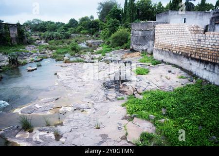 Ruhiger Fluss, Der Durch Die Üppige Landschaft Neben Urban Encroachment Fließt Stockfoto