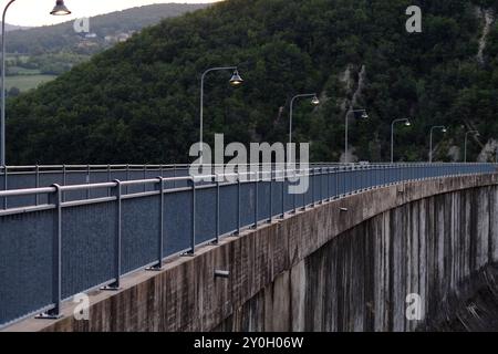 Lange, geschwungene Damm-Mauer mit Laternenpfosten an der Spitze, beleuchtet im Abendlicht. Die Mauer reicht in die Ferne und unterstreicht ihre beeindruckende Wirkung Stockfoto