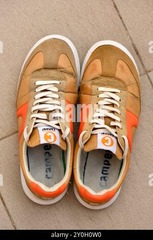 Ein Paar alte orange Camper-Schuhe von oben mit Vintage-Turnschuhen und lässigen urbanen Schuhen Stockfoto