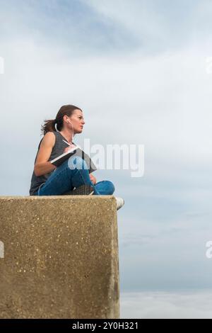 Frau, die draußen in einem Notizbuch oder Tagebuch sitzt Stockfoto