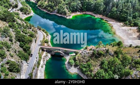 Aus der Vogelperspektive einer alten Brücke, die zwei Seiten eines türkisfarbenen Sees verbindet Stockfoto