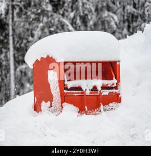 Gjerstad, Norwegen - 07. Januar 2023: Orangener Recyclingbehälter im Tiefschnee Stockfoto