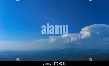 Große Kumulonimbus-Wolkenbildung, die sich über einem Bergtal entwickelt Stockfoto