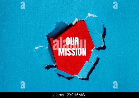 Unsere Botschaft auf zerrissenem blauem Papier mit rotem Hintergrund. Konzeptionelles unser Missionssymbol. Kopierbereich. Stockfoto