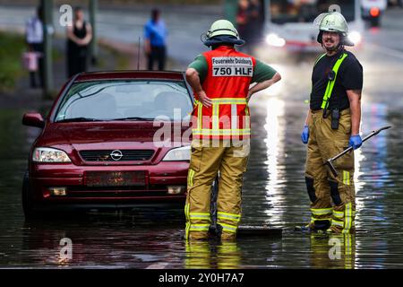 Duisburg, Deutschland. September 2024. Ein Auto steckt in Hochwasser in einer Höhle fest, während die Feuerwehr die Mannlochabdeckungen öffnet, damit das Wasser nach einem Sturm abfließen kann. Quelle: Christoph Reichwein/dpa/Alamy Live News Stockfoto