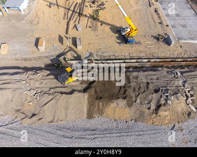 Bauarbeiten an der Küste. Schwere Maschinen arbeiten, um das Fundament vor Wasser und Sturmwellen zu stärken. Blick von der Drohne. Stockfoto