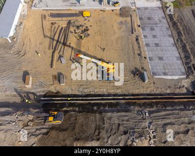 Bauarbeiten an der Küste. Schwere Maschinen arbeiten, um das Fundament vor Wasser und Sturmwellen zu stärken. Blick von der Drohne. Stockfoto