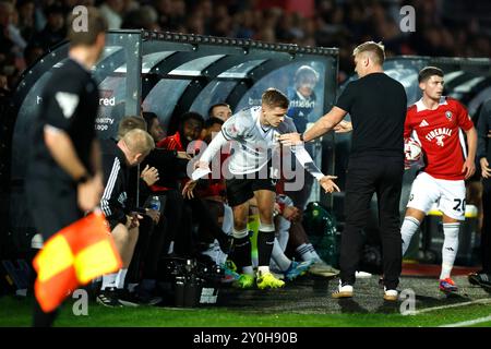 Joe Tomlinson (Mitte) von Milton Keynes Dons stößt beim Spiel der Sky Bet League Two im Peninsula Stadium in Salford auf das Dugout von Salford City. Bilddatum: Montag, 2. September 2024. Stockfoto