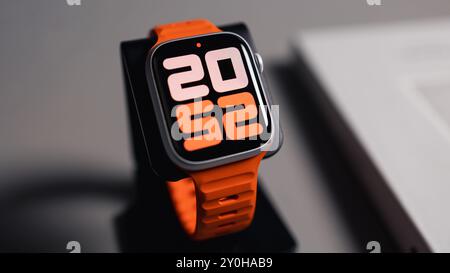 LONDON - 26. AUGUST 2024: Apple Watch mit leuchtend orangefarbenem Bandarmband und Uhrenblatt Stockfoto