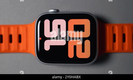 LONDON - 26. AUGUST 2024: Apple Watch mit leuchtend orangefarbenem Bandarmband und Uhrenblatt Stockfoto