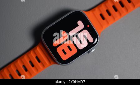 LONDON - 26. AUGUST 2024: Apple Watch mit leuchtend orangefarbenem Bandarmband und Uhrenblatt Stockfoto