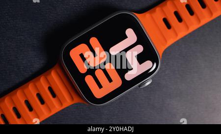 LONDON - 26. AUGUST 2024: Apple Watch mit leuchtend orangefarbenem Bandarmband und Uhrenblatt Stockfoto