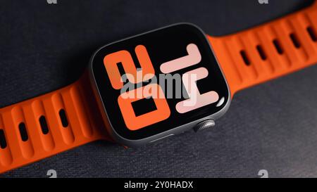 LONDON - 26. AUGUST 2024: Apple Watch mit leuchtend orangefarbenem Bandarmband und Uhrenblatt Stockfoto