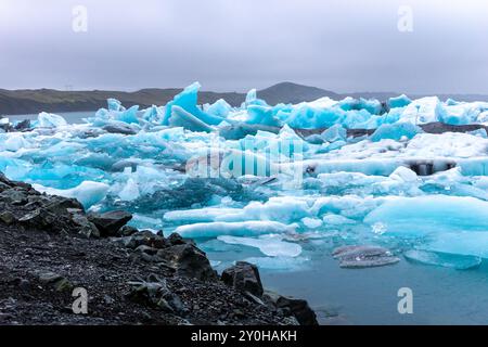 Gletscherlagune Jokulsarlon in Island, mit leuchtend blauen Eisbergen aus zurückziehendem Gletscher, die in Richtung Atlantik driften. Stockfoto