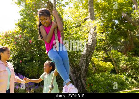 Draußen spielen, Mädchen am Seil schwingen, während Familie im Garten zusieht Stockfoto