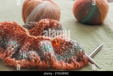 Bunte Garnkugel mit Strickjacke und Stricknadeln. Alpaka- und Wollgarn mit wunderschönem Strickmuster. Verlaufshäkeln Stockfoto