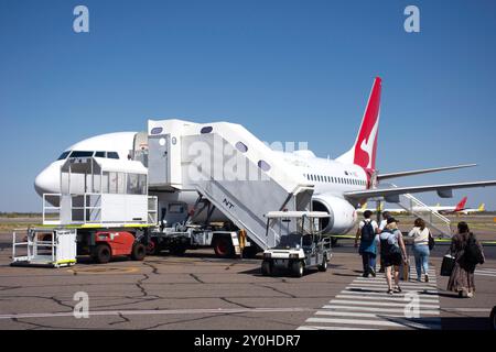 Passagiere, die am Flughafen Alice Springs, Santa Teresa Road, Alice Springs, Northern Territory, Australien an Bord eines Qantas Boeing 737-800-Flugzeugs gehen Stockfoto