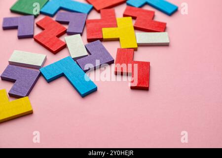 Bunte hölzerne Puzzleteile auf rosa Hintergrund. Leerzeichen für Text Stockfoto