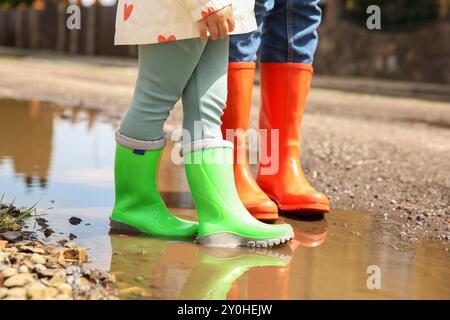 Mutter und Tochter tragen Gummistiefel, stehen draußen in der Pfütze, Nahaufnahme Stockfoto