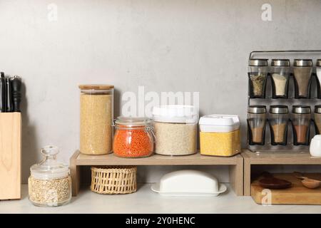 Verschiedene Arten von Getreide und Hülsenfrüchten in Behältern auf einem hellen Marmortisch Stockfoto