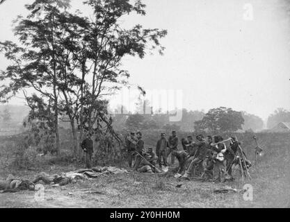 Gewerkschaftssoldaten standen in der Nähe der Leichen toter Konföderierter Soldaten während des Amerikanischen Bürgerkriegs Stockfoto