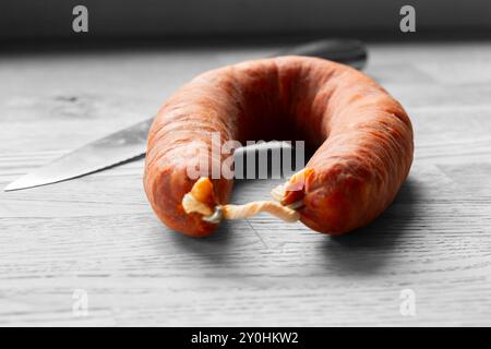 Spanisches Chorizo auf einem hölzernen Schneidebrett mit einem Messer. Bearbeitet mit selektiver Farbe Stockfoto