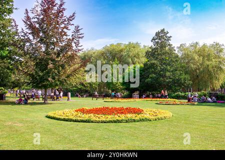 Eine malerische Parklandschaft an einem sonnigen Tag mit blühenden Blumenbeeten, üppigem grünem Gras und zahlreichen Menschen, die Freizeitaktivitäten genießen. Winchester Großbritannien Stockfoto