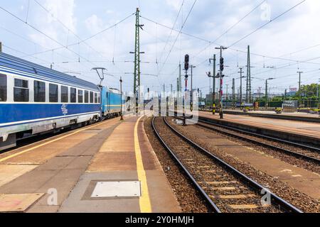 Zugwagen für Budapest (Ungarn) nach Timisoara (Rumänien) fahren an einem sonnigen Sommertag am Bahnhof Keleti mit Bahngleisen und Bahnsteig. Stockfoto