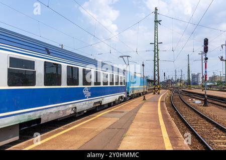 Zugwagen für Budapest (Ungarn) nach Timisoara (Rumänien) fahren an einem sonnigen Sommertag am Bahnhof Keleti mit Bahngleisen und Bahnsteig. Stockfoto