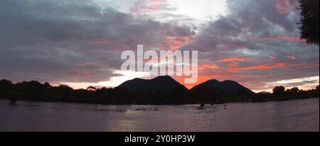 Wolken, die von der aufgehenden Sonne erhellt werden, erwecken den alten Spruch: "Roter Himmel am Morgen, Hirten warnen". Hitze und Wolken bilden sich tagsüber Stockfoto